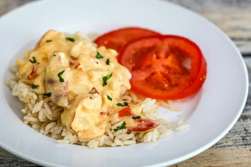 lobster newburg over rice with sliced tomatoes on the side.