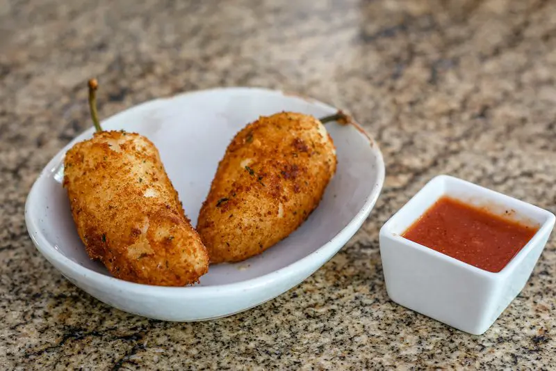 crispy deep-fried jalapeño poppers with cheddar and cream cheese filling and salsa on the side.