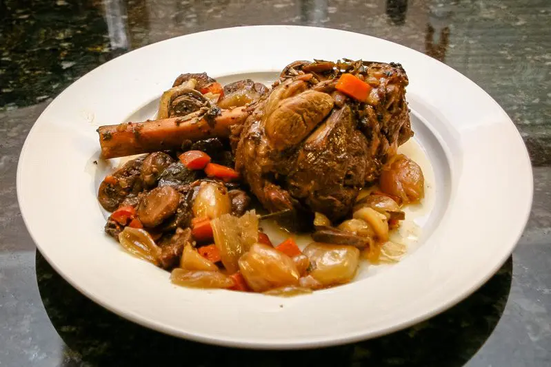 crock pot lamb shank with rosemary and vegetables on a plate