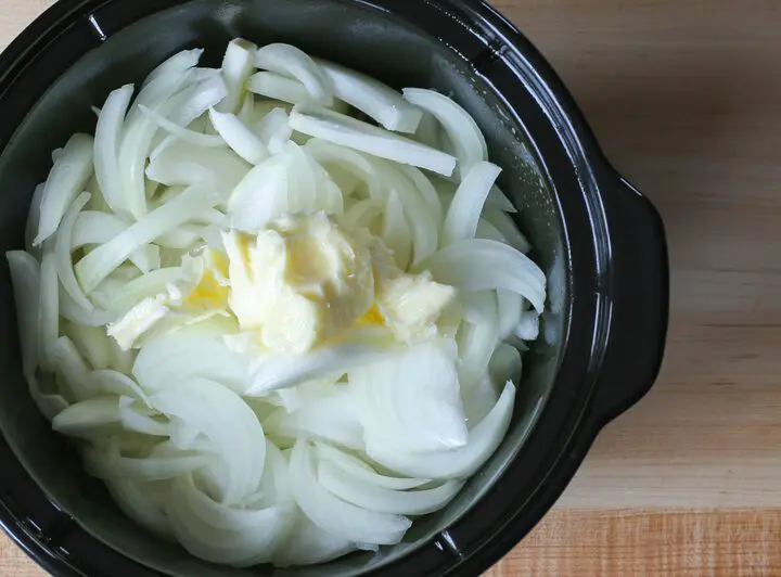 preparing slow cooker onion soup with onions and butter in the crockpot