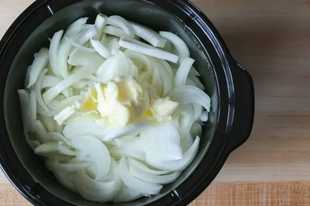 preparing slow cooker onion soup with onions and butter in the crockpot