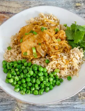 slow cooker chicken with curry flavor on a plate with rice and peas