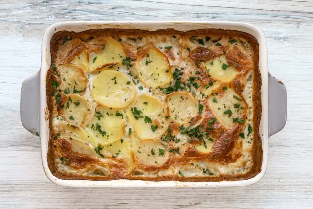 Dauphinoise potatoes are garnished with fresh parsley and ready to serve.
