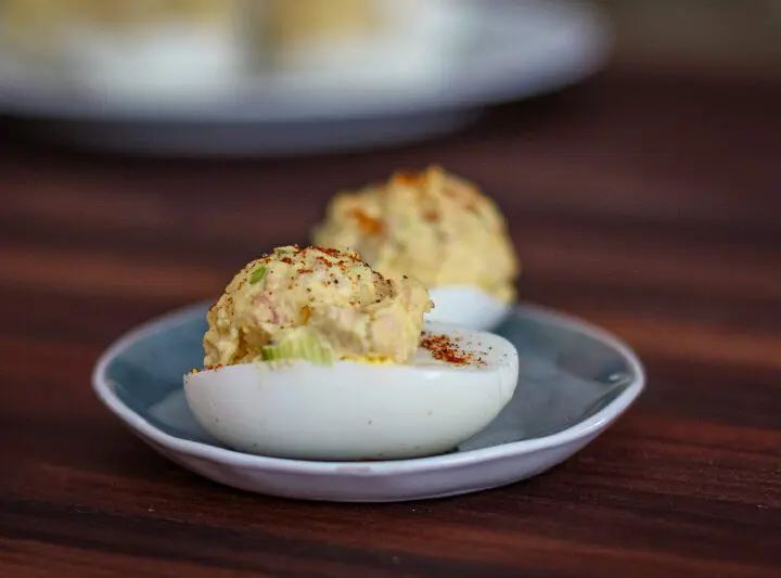 deviled eggs with ham on a small dish with more in the background