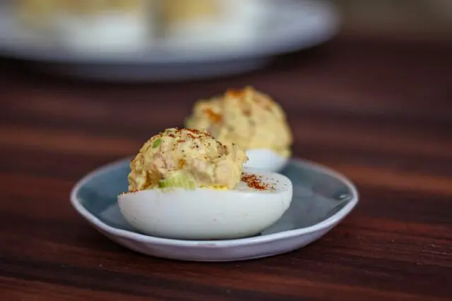 deviled eggs with ham on a small dish with more in the background