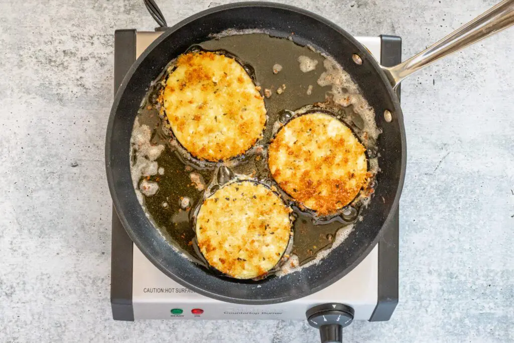 frying the eggplant slices in a skillet.