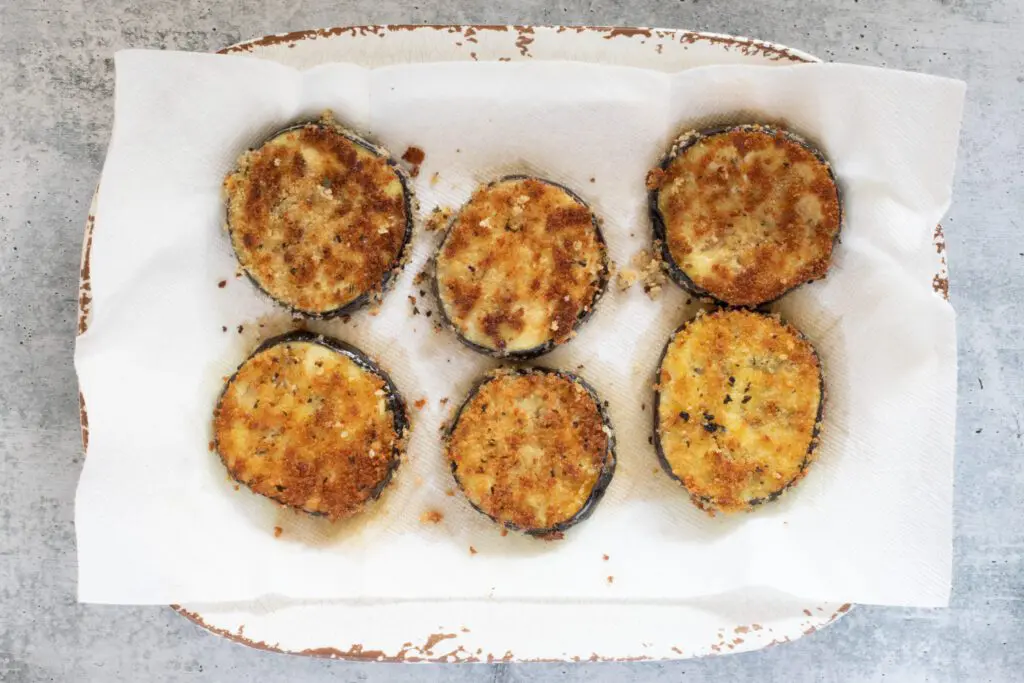 fried panko breaded eggplant slices draining on paper towels.