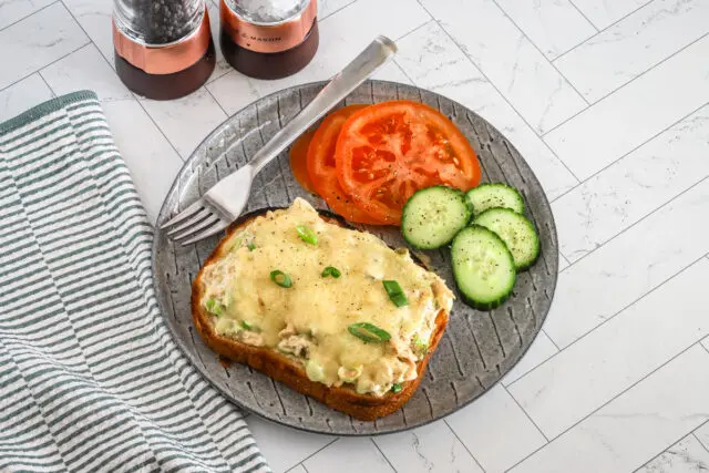 Tuna melt sandwiches, open-faced, with sliced tomatoes and cukes on the side.