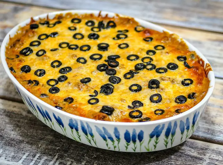 an enchilada casserole covered with cheese and sliced olives.