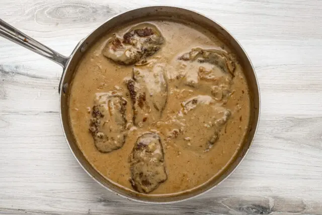 Smothered pork chops simmered with the onions, sauce, and cream.