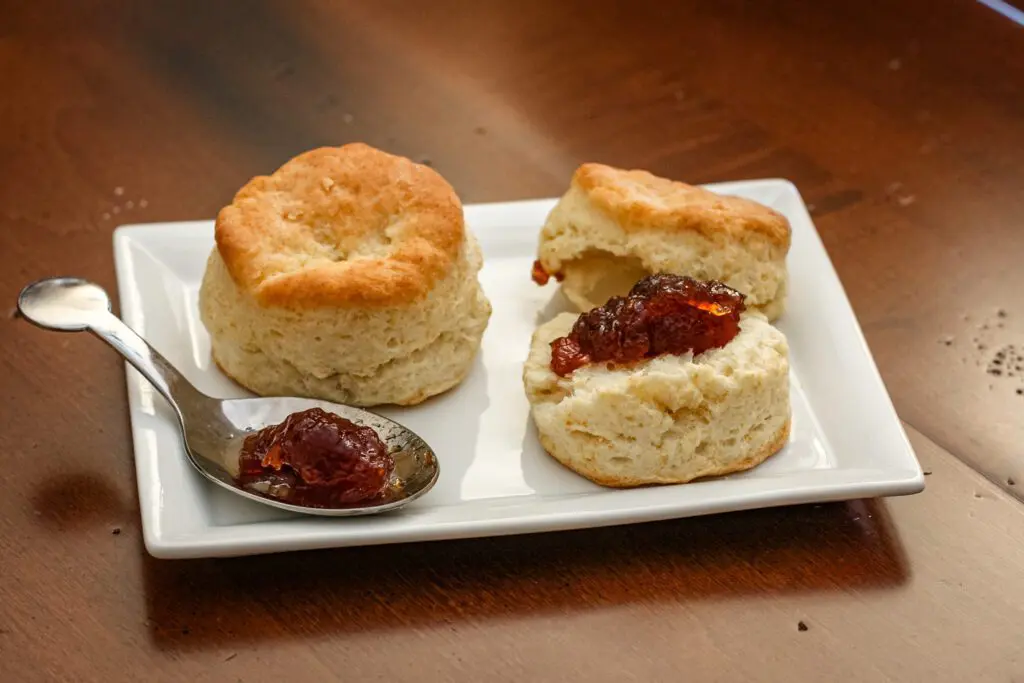 flaky buttermilk biscuits on a plate with jam or jelly