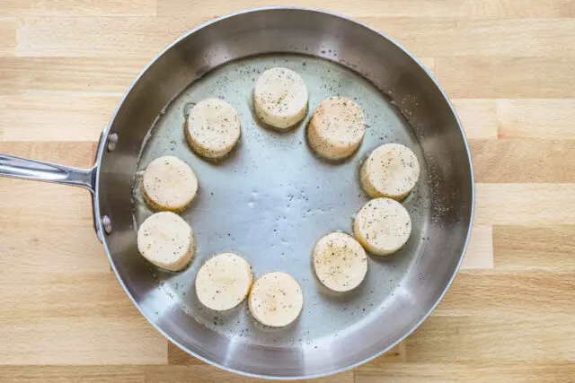 Duck fat and shaped potatoes are added to a large skillet.