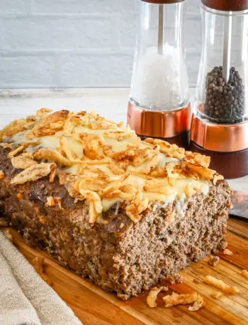 Sliced French onion meatloaf with Gruyère cheese and fried onion topping.