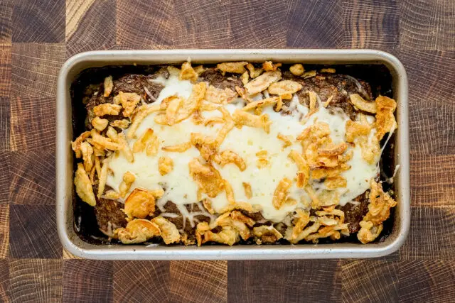 Overhead shot of the French onion meatloaf with melted Gruyere cheese and crispy fried onions.