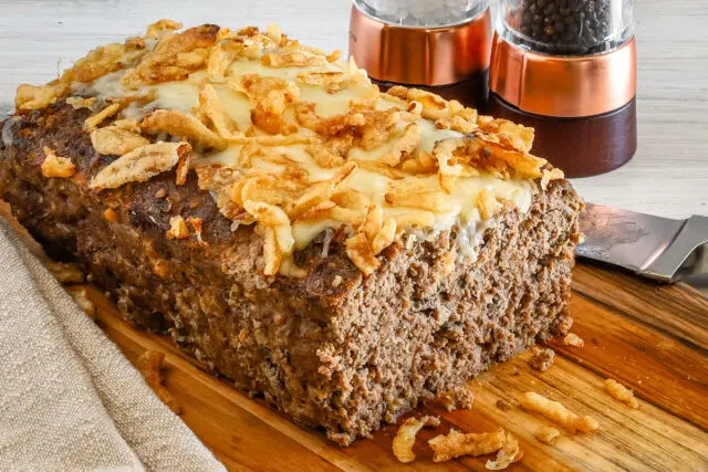 Sliced French onion meatloaf with Gruyère cheese and fried onion topping.