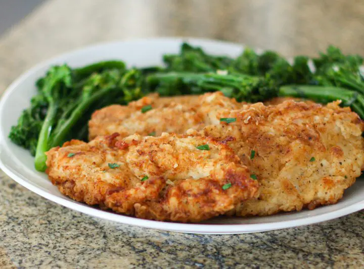 fried chicken breast cutlets on a plate with broccolini