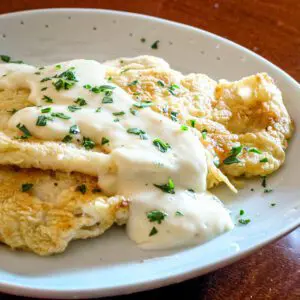 fried sole with parmesan sauce on a plate with parsley garnish