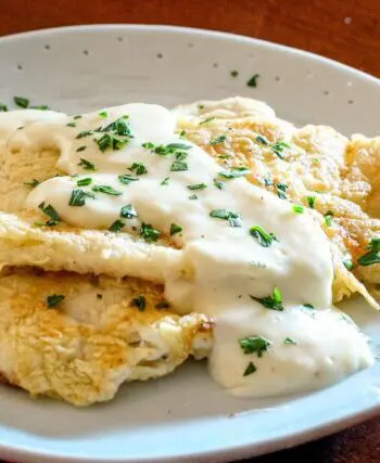 pan fried sole on a plate with parmesan sauce