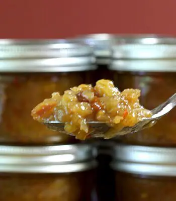 green tomato chutney in jars with spoon of chutney in foreground