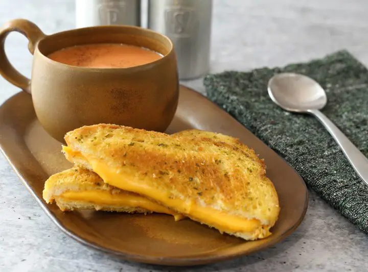 a basic grilled cheese sandwich on a sandwich plate with tomato soup