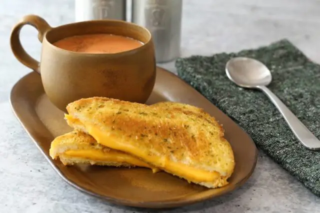 a basic grilled cheese sandwich on a sandwich plate with tomato soup