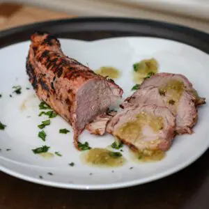 grilled pork tenderloin on a plate with salsa verde