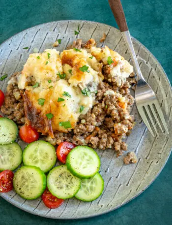 Ground beef casserole with cheesy mashed potato topping and some cucumbers and tomatoes on the side.