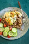 Ground beef casserole with cheesy mashed potato topping and some cucumbers and tomatoes on the side.