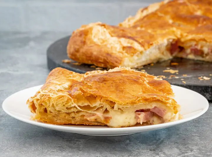 a slice of ham, gruyere, and fig tart on a plate