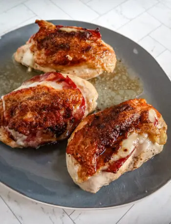 Serving tray with skin-on chicken breasts with capicola and provolone.