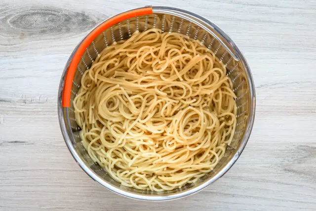 Cooked spaghetti in a strainer.