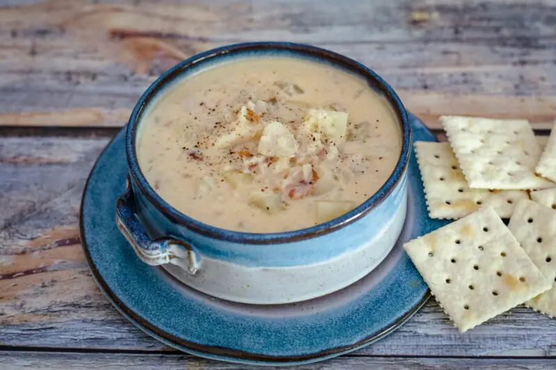 A bowl of fish chowder with crackers on the side