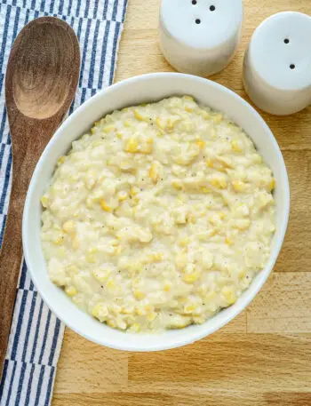 Homemade cream style corn in a serving dish with spoon.