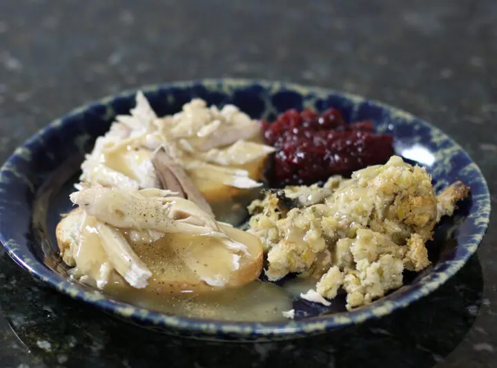 a hot turkey sandwich with leftover stuffing, cranberry sauce, and gravy