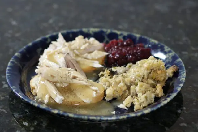 a hot turkey sandwich with leftover stuffing, cranberry sauce, and gravy