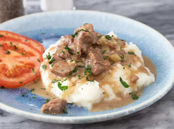 instant pot beef tips with mashed potatoes and fresh sliced tomatoes