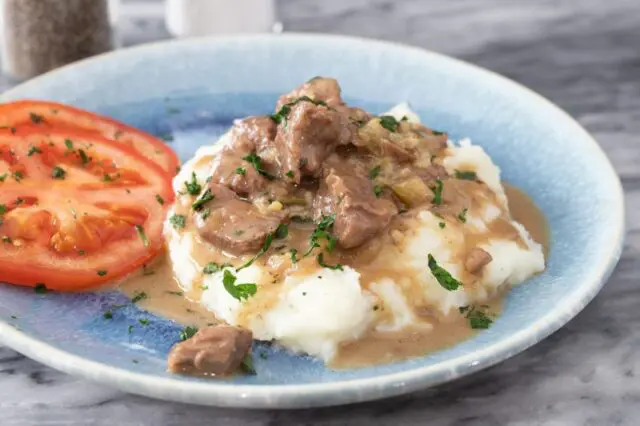 instant pot beef tips with mashed potatoes and fresh sliced tomatoes