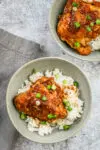 Instant Pot chicken adobo is plated in a bowl with rice and green onions.