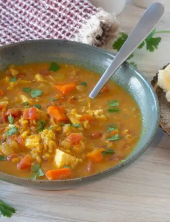 a bowl of mulligatawny soup with naan bread on the side