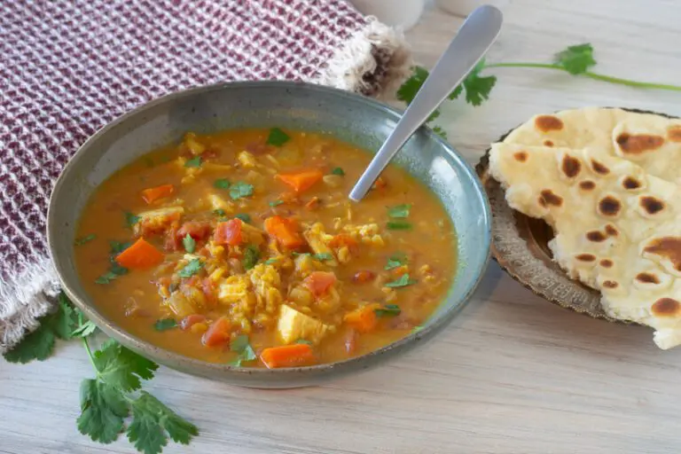 a bowl of mulligatawny soup with naan bread on the side