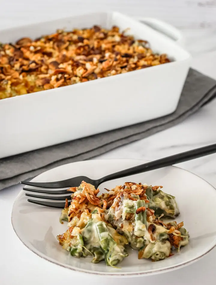 Green bean casserole on a plate with a serving dish in the background.