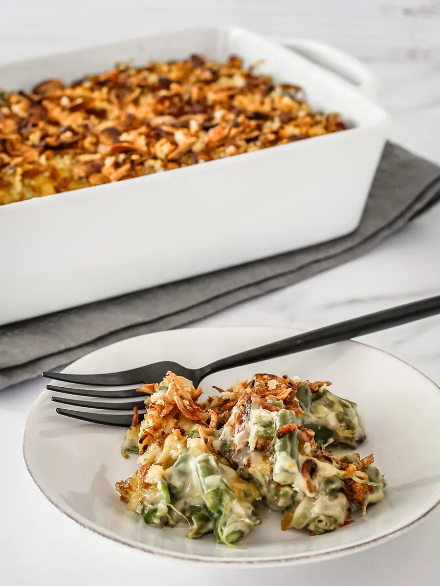 Green bean casserole on a plate with a serving dish in the background.