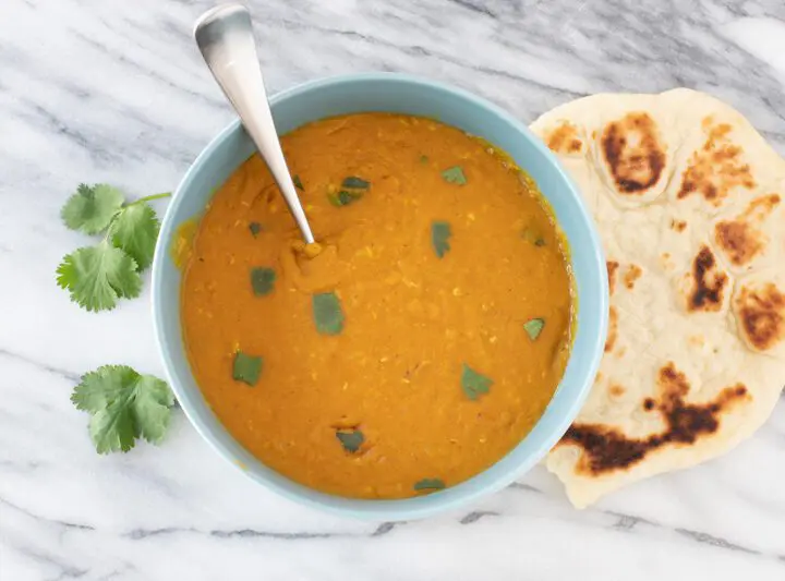 instant pot red lentil dal in a bowl with naan bread on the side