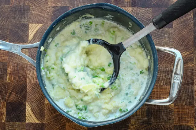 Irish champ preparation: mashing the potatoes with warm milk, scallions, and butter.