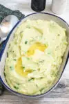 A serving bowl with Irish champ mashed potatoes and scallions with butter melting on top.