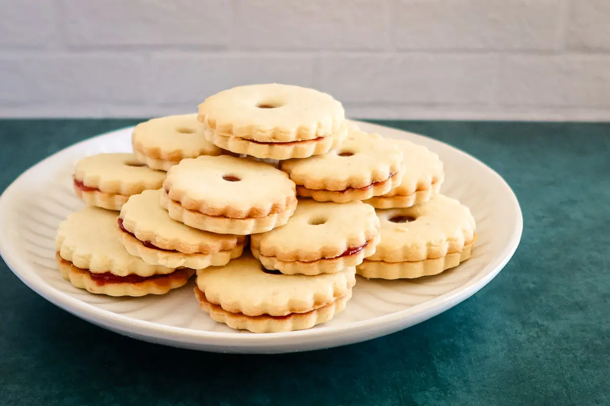 Filled jammie dodgers with raspberry jam on a plate.