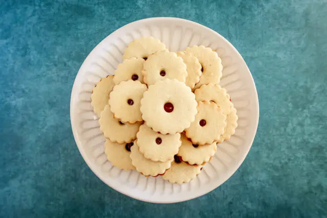 Filled jammie dodgers with raspberry jam on a plate.