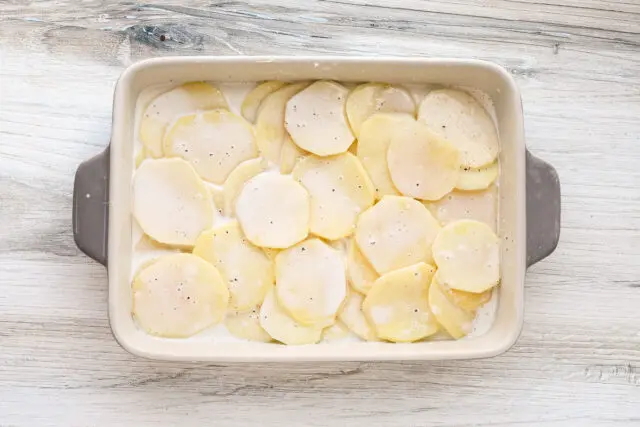 Layered potatoes and seasoned cream for dauphinoise potatoes.