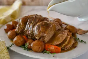 leg of lamb with gravy pouring over it