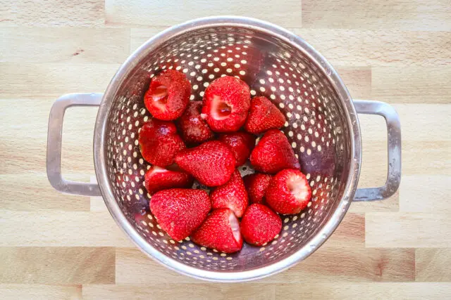 Hulled and rinsed strawberries in a colander.